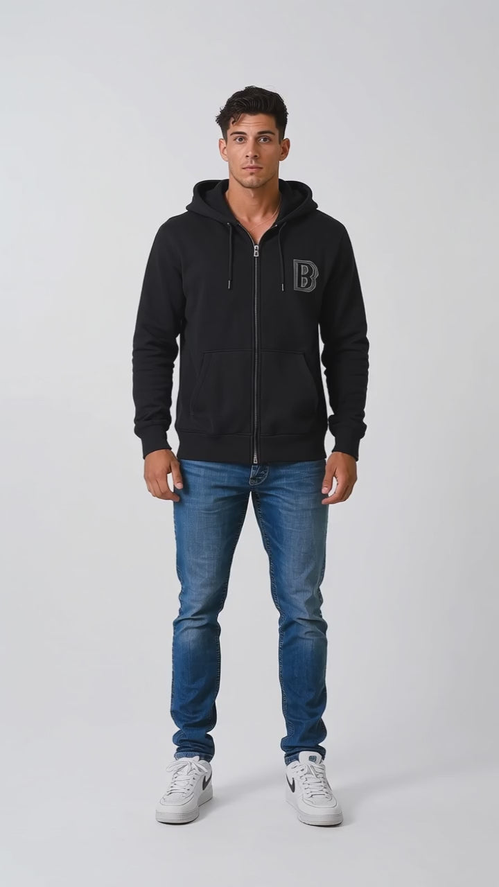Model wearing the black DOMIN8NY Crown zip-up hoodie, front view
